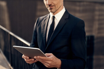 Close up of confident mature businessman working on digital tablet while standing outdoors