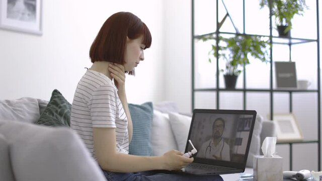Online drug prescribing. Pretty suffering sick woman with a sore throat, using oral spray for treatment, having a video call from home, listening to the male doctor, giving recommendations