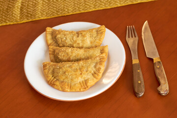 Three freshly made empanadas ready to eat, on your porcelain plate. Argentine gastronomy concept.