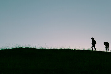 Silhouette man and woman in the mountains and hiking.