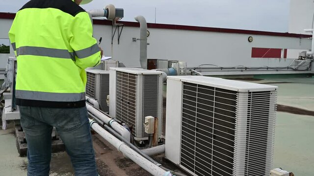 Air conditioning technicians repair and maintain condensing units outside the building, engineers inspect the operation of ventilation fans.