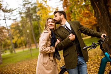 Young couple in the autumn park with electrical bicycle