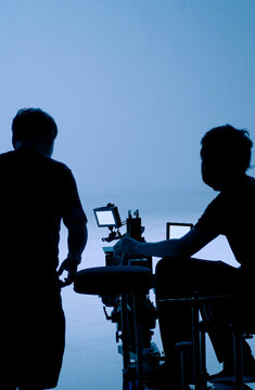 Video production behind the scenes. Making of TV commercial movie that film crew team lightman and cameraman working together with film director in studio. film production concept. Silhouette style.