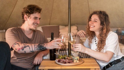 A happy couple resting in a tent at glamping. Wine and food
