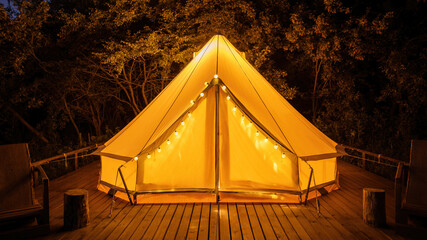 Glamping at night, glowing tent with chairs in front of it - obrazy, fototapety, plakaty