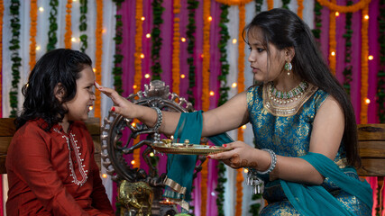 Indian families celebrating Raksha Bandhan festival a festival to celebrate the bond between brother and sister. Rakhi celebration in India. Feeding sweets, applying tikka.