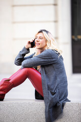 relaxed woman talking on the cell phone in the street sitting on the street