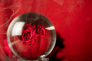crystal ball reflecting a bouquet of red roses and smoke, selective focus.