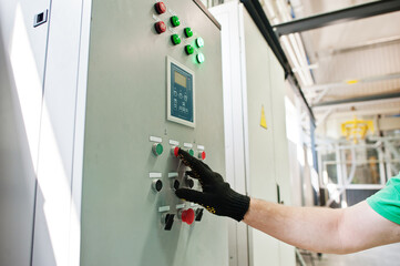 Man worker press button equipment of the switchboard. Strip the cable channels for the wires.