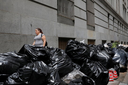 A person walks by discarded bags of trash in the Financial District after The United Nations released the findings of the Intergovernmental Panel on Climate Change's (IPCC) latest report in Manhattan, New York City