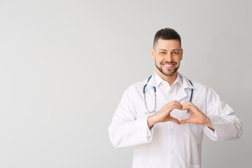 Cardiologist making heart with his hands on light background