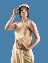 Beautiful young woman in stylish cap on color background