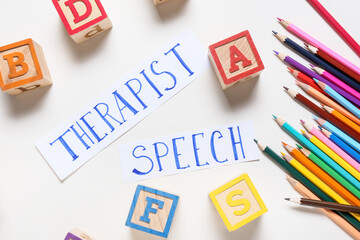 Text SPEECH THERAPIST with cubes and pencils on white background