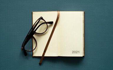 2021 calendar with space for text, brown bookmark, brown glasses, on a painted background, photo from above