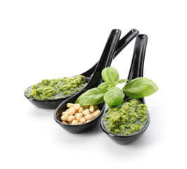 Spoons with fresh pesto sauce and ingredients on white background