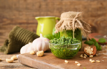 Board with fresh pesto sauce and ingredients on wooden background