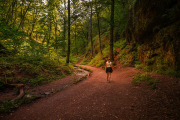 Eine Frau l&auml;uft durch einen romantischen Wald mit einem Bach neben dem Weg
