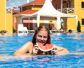beautiful wet girl eating watermelon on the background of the pool