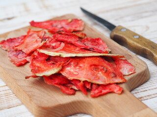 Dried and fresh slices of watermelon on a kitchen board on a wooden white table.