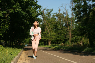 Fototapeta na wymiar Sporty young woman listening to music while running outdoors