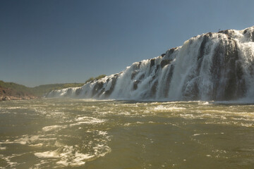 Navigating the rapids. The majestic Mocona falls seen from the boat. The rocky waterfall white water, strong river current flowing across the jungle.