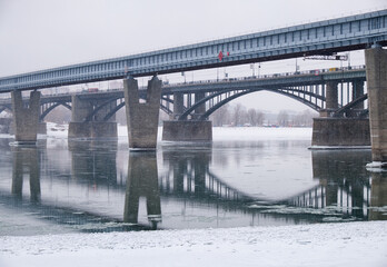 Photo  of the frozen Ob River with road and subway bridges on a winter snowy day. Novosibirsk, Russia.