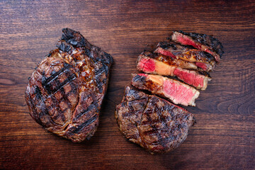 Modern style barbecue dry aged wagyu rib-eye beef steaks served as top view on a wooden design...