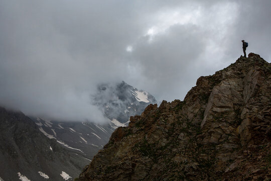 Active recreation. Silhouette of a tourist with a backpack on the mountain. Cloudy cloudy day. Trekking route, hiking.
