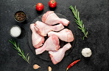 raw chicken legs with spices on a stone background