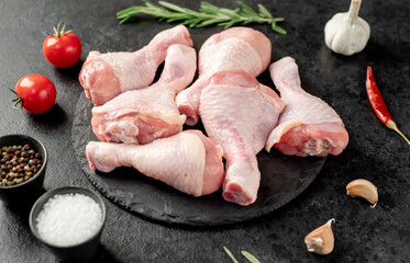 raw chicken legs with spices on a stone background