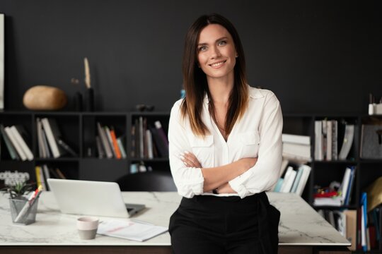 Confident Stylish European Middle Aged Woman Standing At Workplace, 30s Lady Executive Leader Manager Looking At Camera