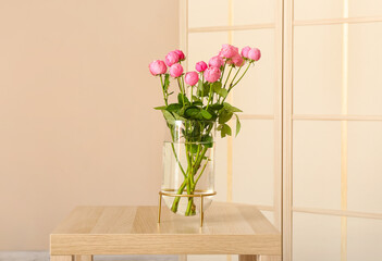 Vase with beautiful peony roses on table in room