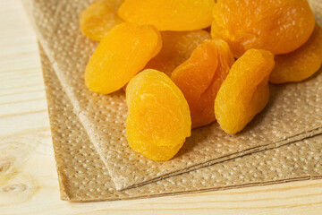 Dried apricots on a paper napkin made of recyclable materials on a wooden tabletop. Healthy snack concept.