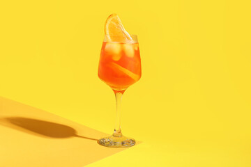Glass of Aperol spritz cocktail on color background
