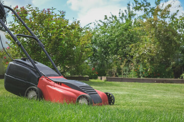 Lawn mower on green grass in a modern garden. Lawn Mowing Machine Gardening, Agriculture, Organic...