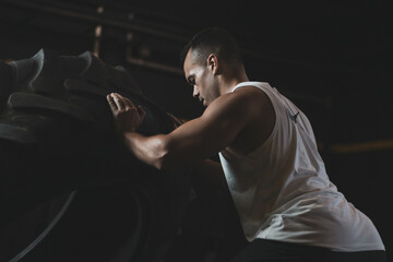 
a Turkish man lifting a wheel inside a gym.