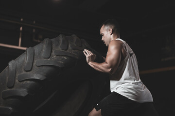 
a Turkish man lifting a wheel inside a gym.