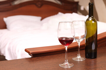 two glasses of red wine on the bedside table in the bedroom of the house