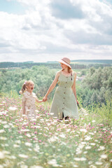 beautiful mother and little daughter in the chamomiles field