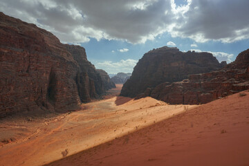 beautiful red gorge in the Wadi Rum desert, beautiful white clouds are in the blue sky, contrasting shadows are on the red sand and relief mountains, the nature of Jordan