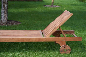 wooden chaise longue in the fresh garden on the green grass. High quality photo