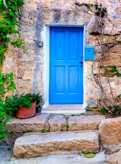 Fototapeta na wymiar Blue door in a rustic facade in Sardinia