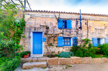 Rustic facade with blue shutters in Sardinia