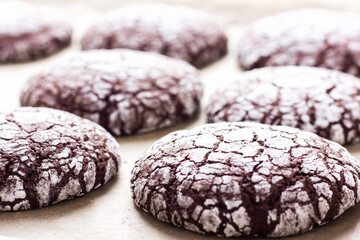 Batch of chocolate crinkle cookies on a parchment paper.