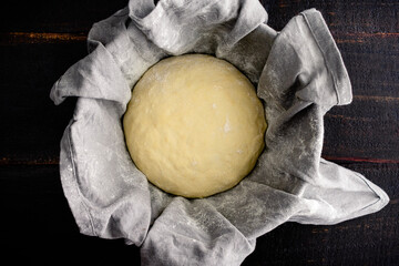French Bread Dough Proofing in a Linen Lined Bowl: Bread dough rising in a proofing bowl lined with...
