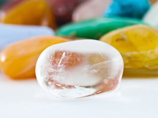 Polished clear transparent quartz gemstone in front of gemstone collection