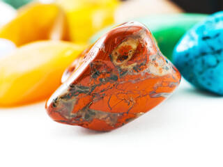 Polished red jasper gemstone in front of gemstone collection