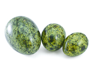 Three different size polished serpentine stone eggs on white background