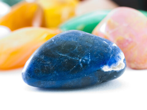 Polished dark blue lazurite gemstone in front of gemstone collection