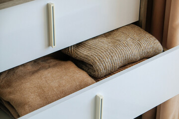 Close up shot of open drawers with neatly folded women's clothes inside. Bedroom dresser with...